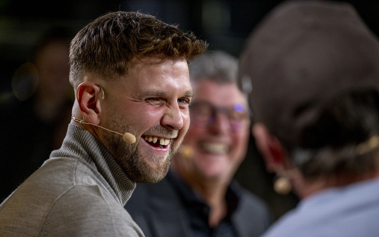 Ein Mann mit Headset lacht herzlich während einer Unterhaltung.