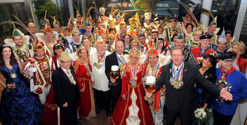 Eine Gruppe von Personen in farbenfrohen Karnevalskostümen posiert mit Bierkrügen.